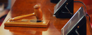 Wooden gavel resting on a courtroom bench.